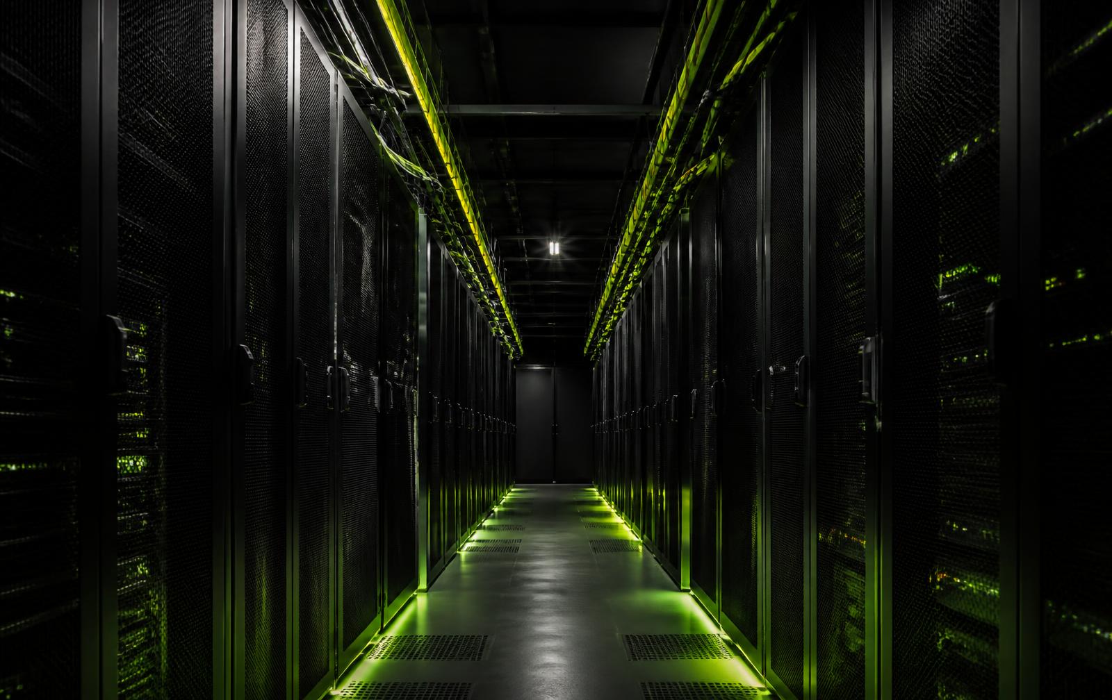Aisle of dark server racks in a data centre, lit by thin green light strips along the cable trays